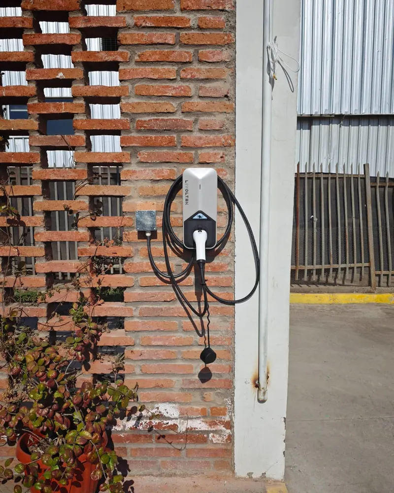 Cargador Livoltek en un muro de ladrillo junto a un galpón industrial