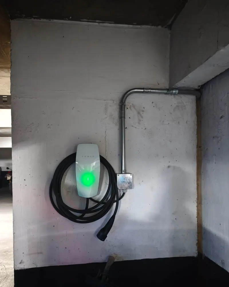 Wall Connector de Tesla encendido en un estacionamiento subterráneo, con canalización EMT