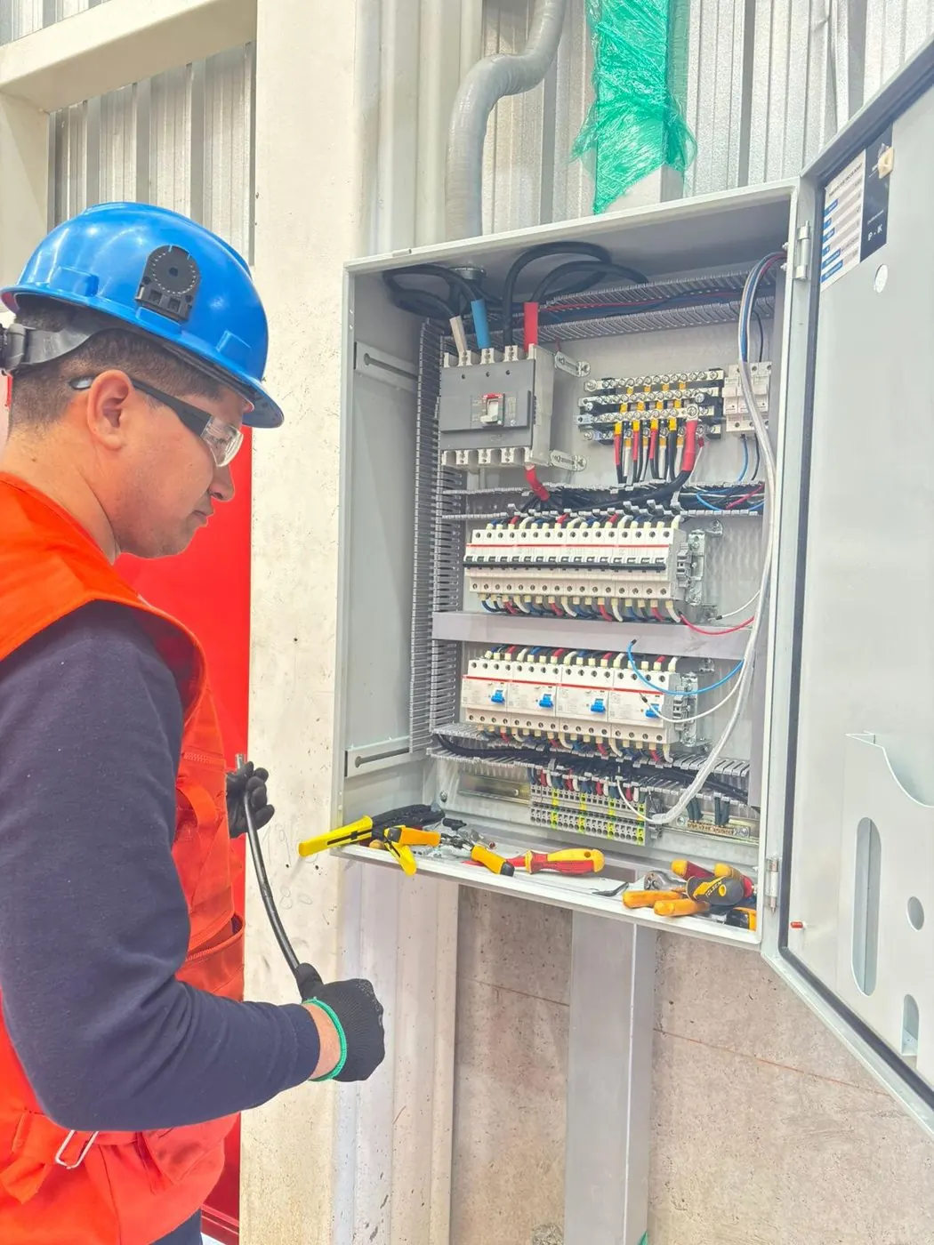 Técnico de MAUCEN con casco y guantes trabajando en un tablero de fuerza