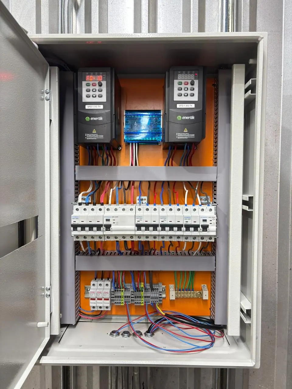 Tablero con dos variadores de frecuencia y protecciones sobre placa naranja